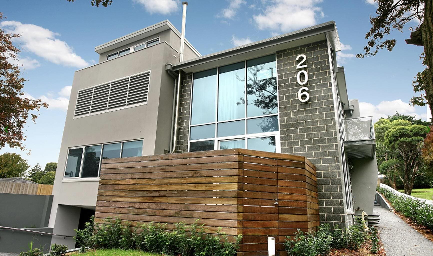Modern two-story house with large windows and gray brick walls.